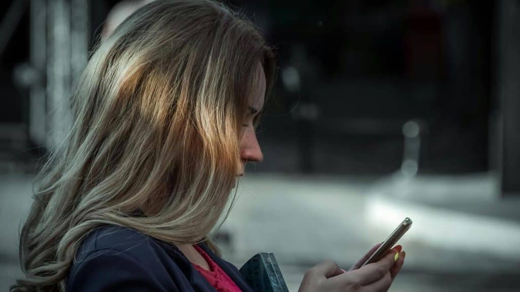 A woman looking at a smartphone in side profile.