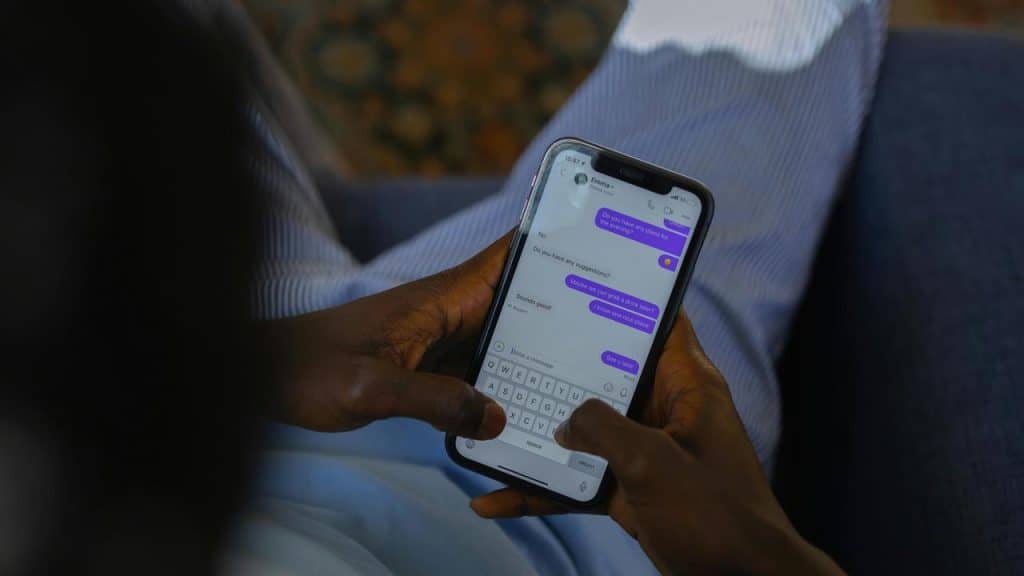 A person texting on a smartphone while sitting indoors
