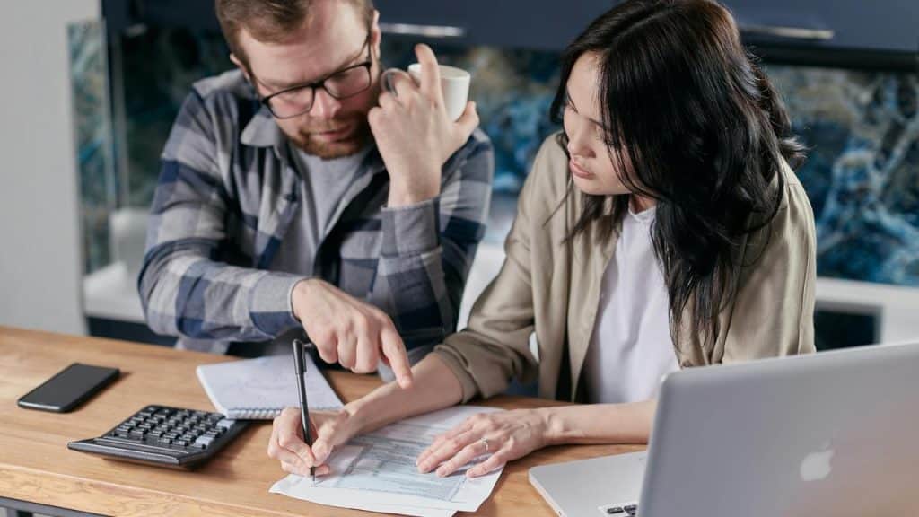 A couple reviewing documents together with a calculator and laptop