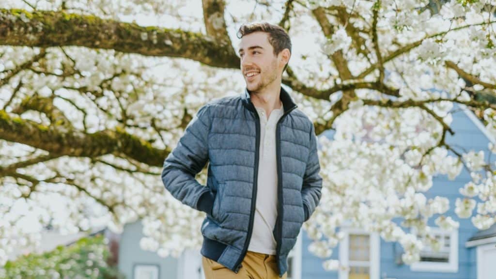 A man in a blue jacket standing on a pathway during daytime.