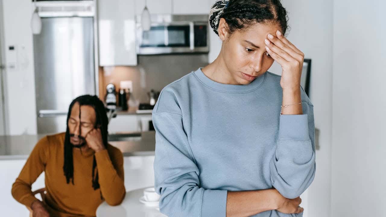 A distraught woman stands in blurred background.