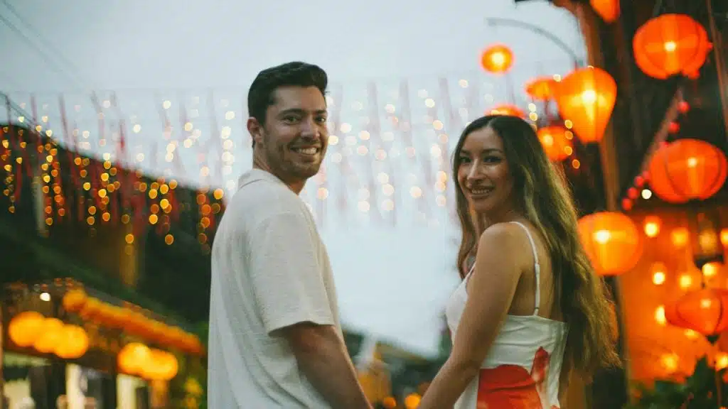 A couple holding hands in a street with lanterns.