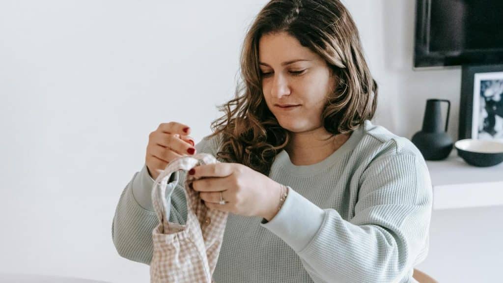A woman holding and examining a piece of fabric indoors.