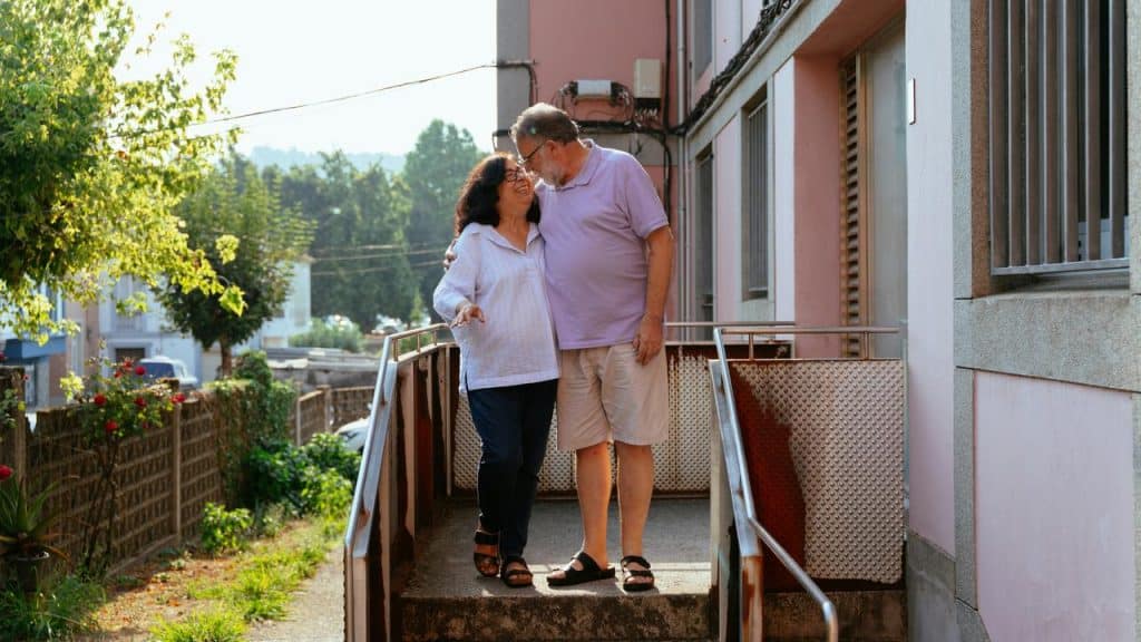 A smiling couple standing close together on an outdoor walkway.