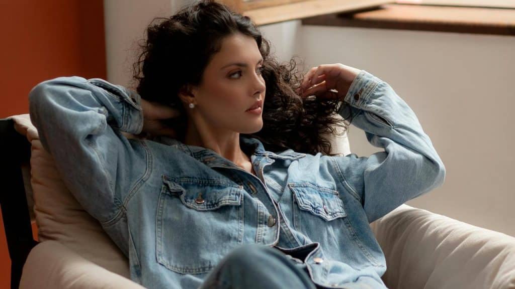 A woman relaxing in a chair wearing a denim jacket.