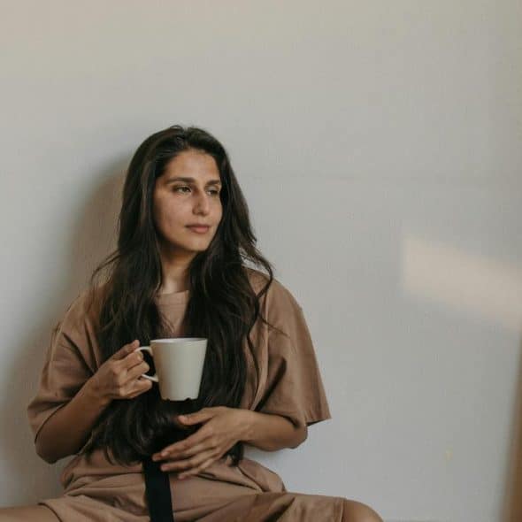A woman sitting on the floor holding a mug