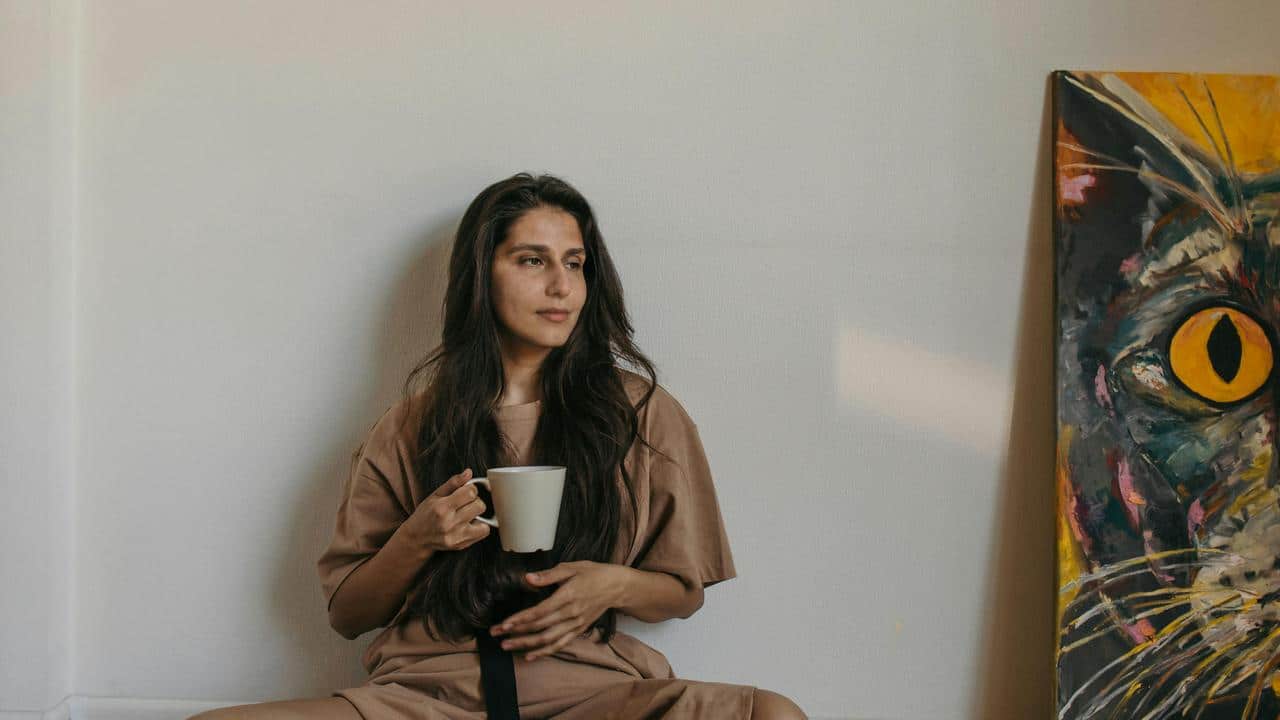 A woman sitting on the floor holding a mug