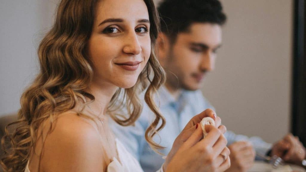 A woman smiling at the camera while sitting at a table with a man.