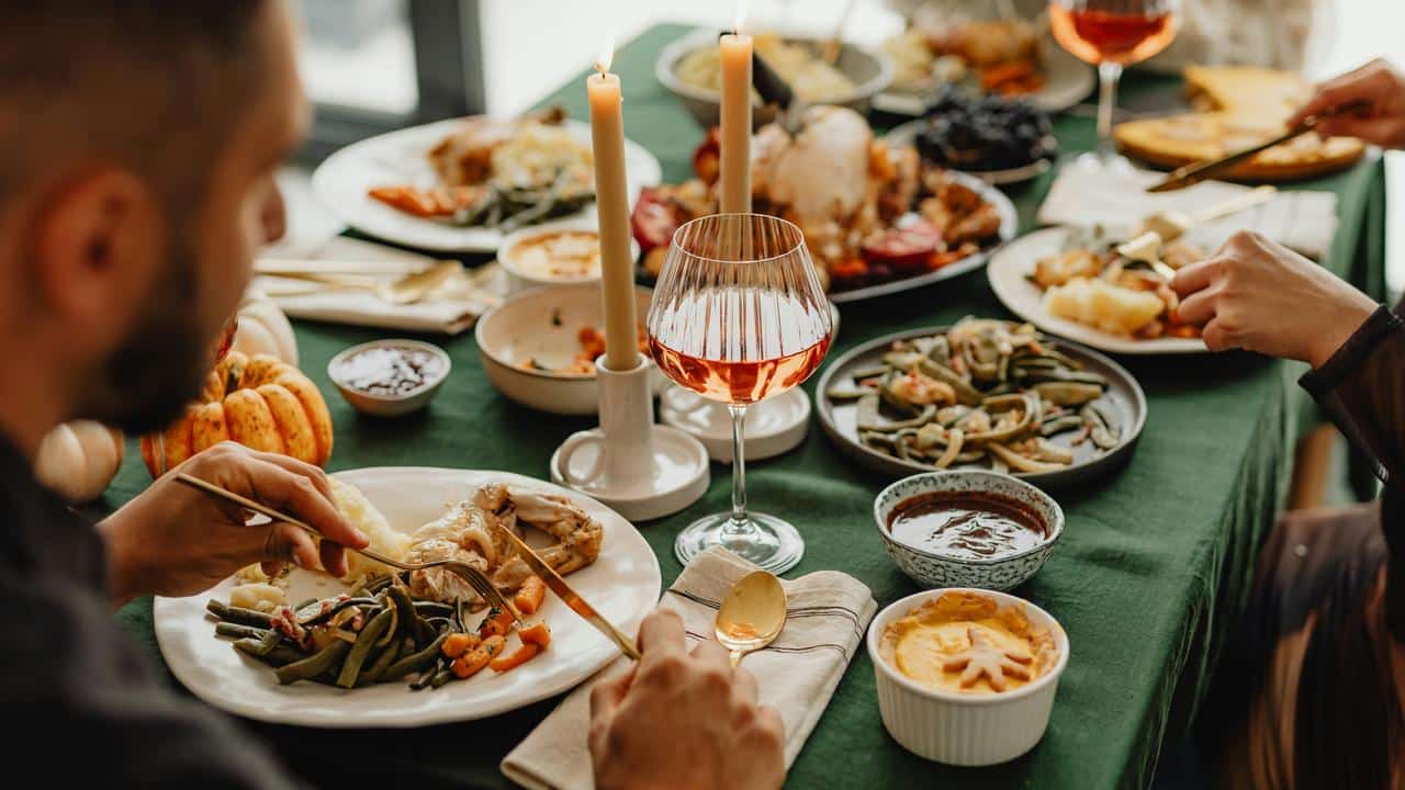 A festive dinner table set with food, wine, and candles.