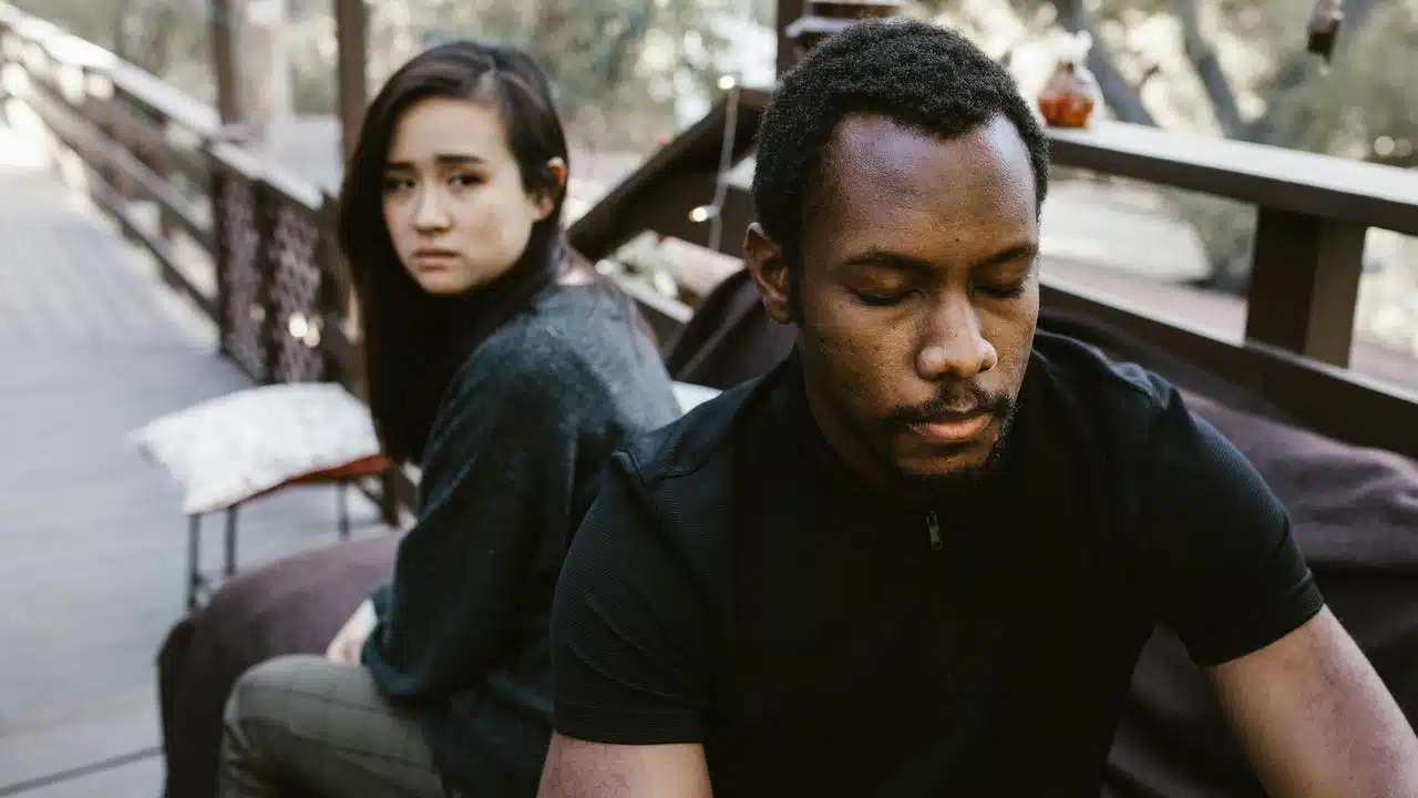 A couple sitting apart looking upset after an argument.