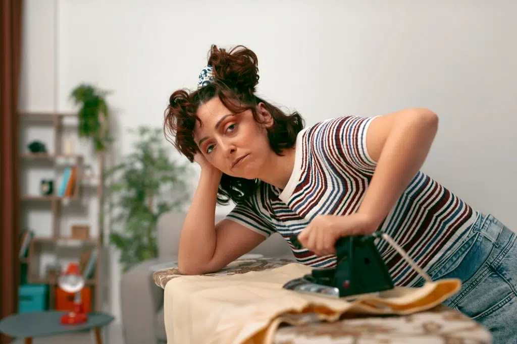 Tired Woman doing chores at home alone ironing clothes