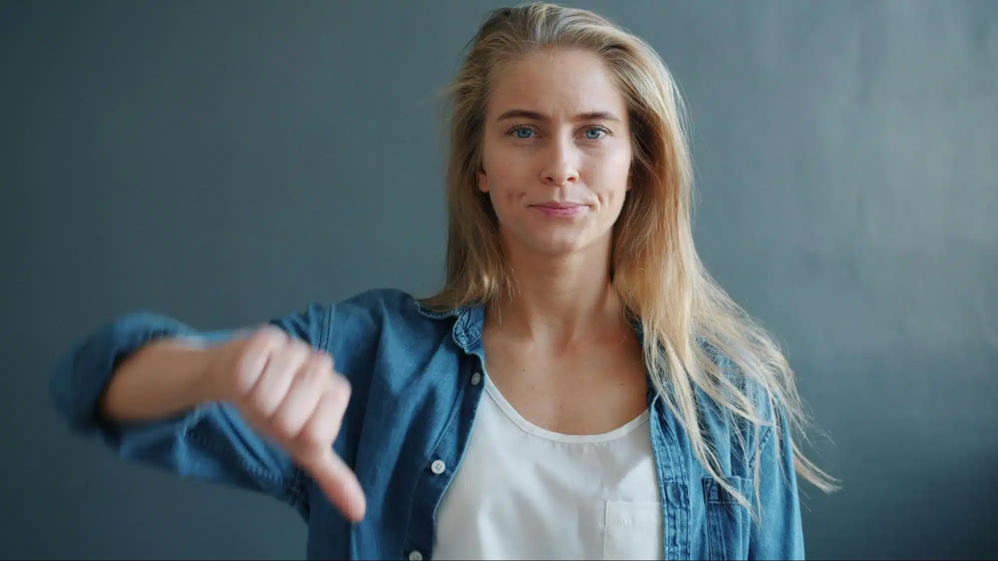 A woman showing a thumbs down gesture.