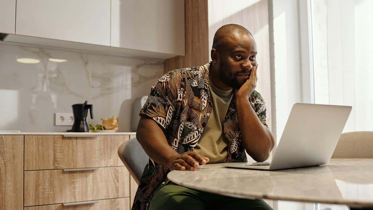 A man sitting at a kitchen table using a laptop