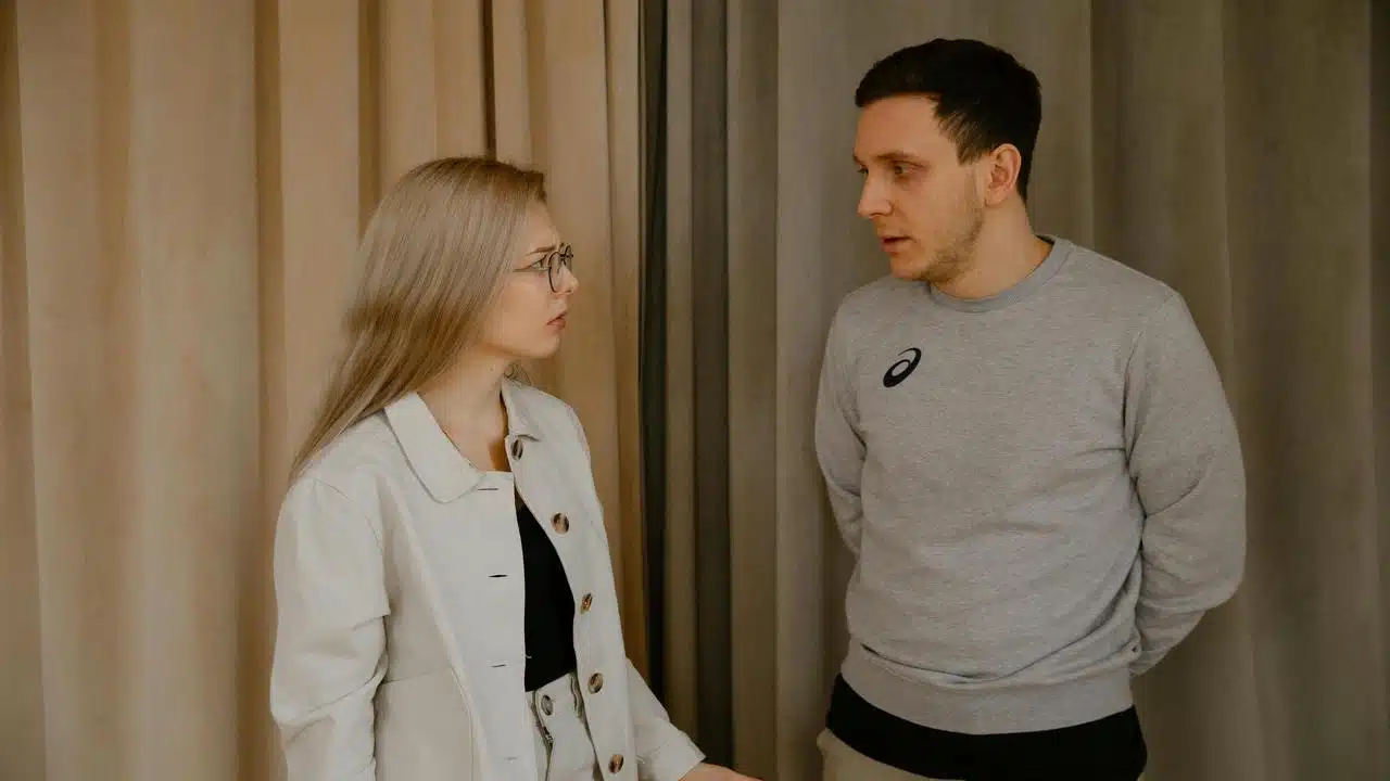 A man and woman having a serious conversation indoors.