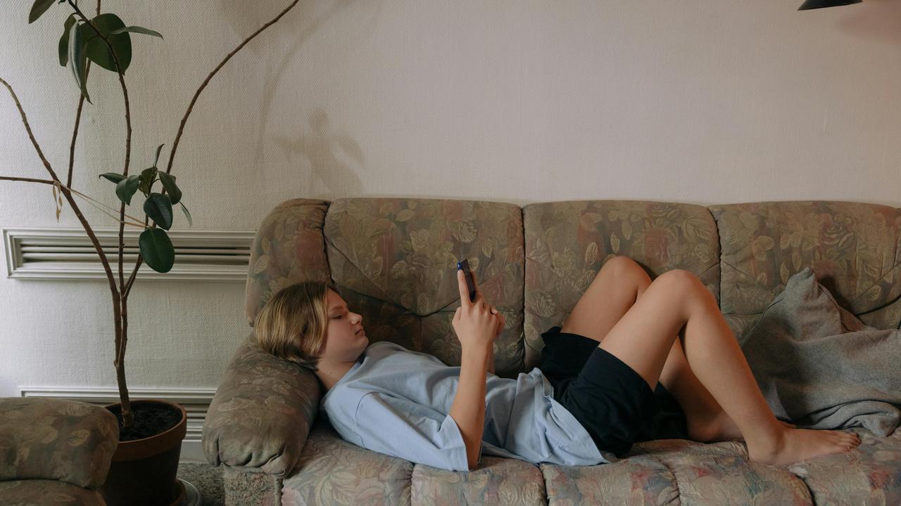 A person lying on a couch using a smartphone.