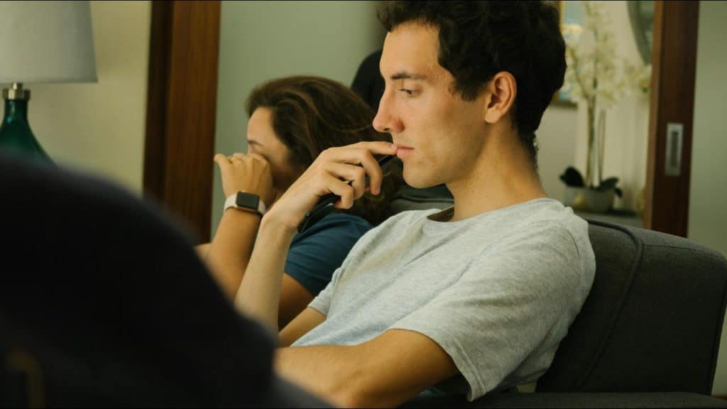 A man sitting thoughtfully while holding a phone.