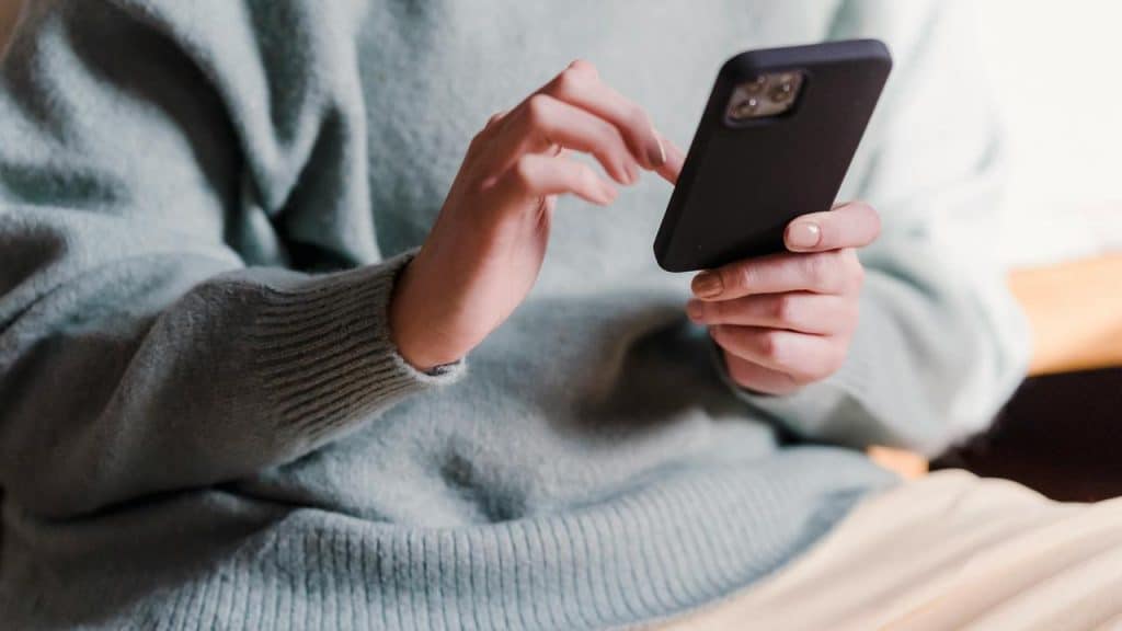 A person in a sweater using a smartphone.