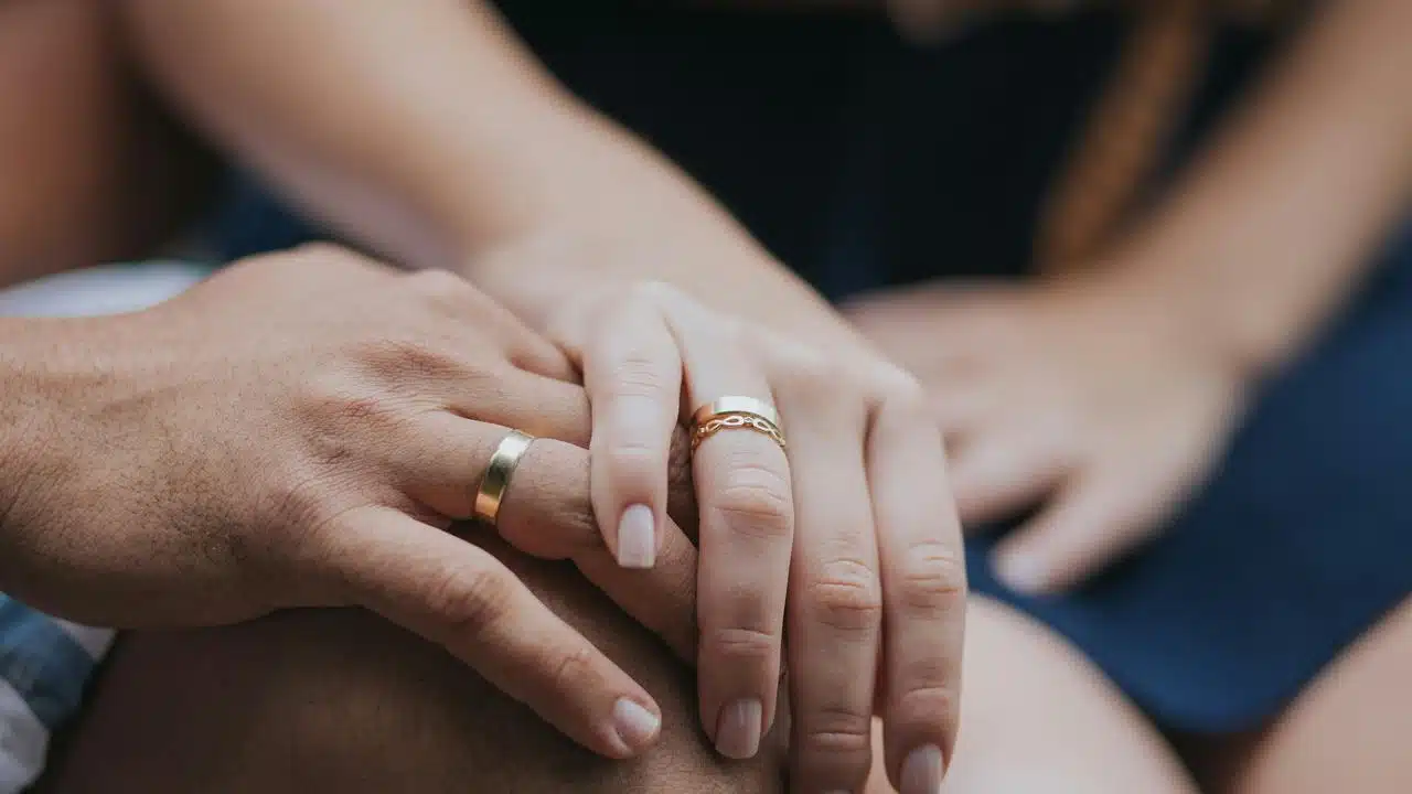 A close-up of two hands with matching rings resting together.