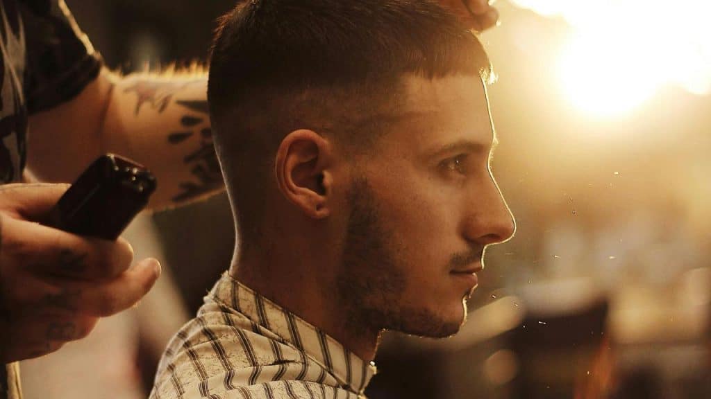 A man getting a haircut with clippers in a barbershop.