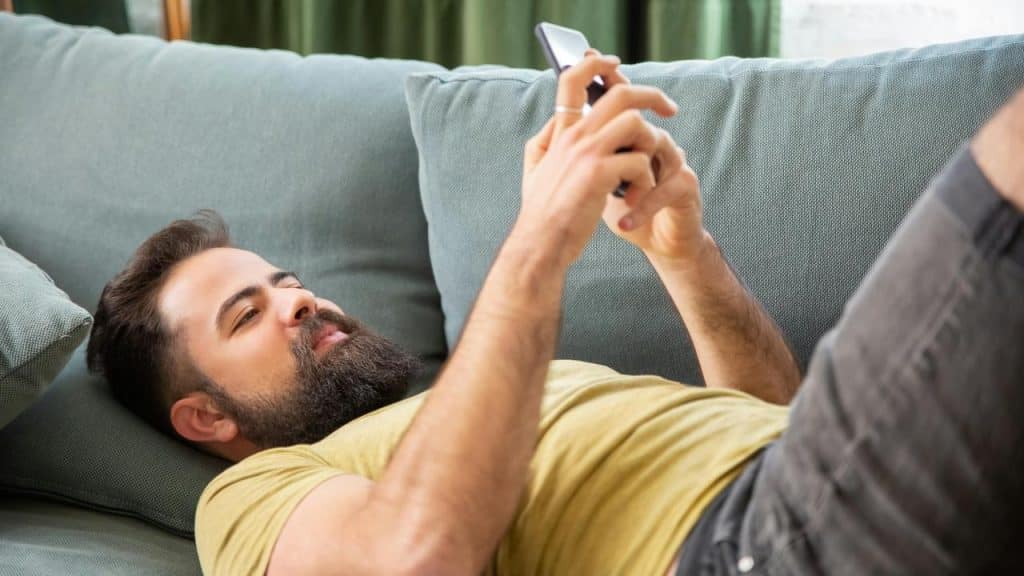 A man lying on a couch using his phone