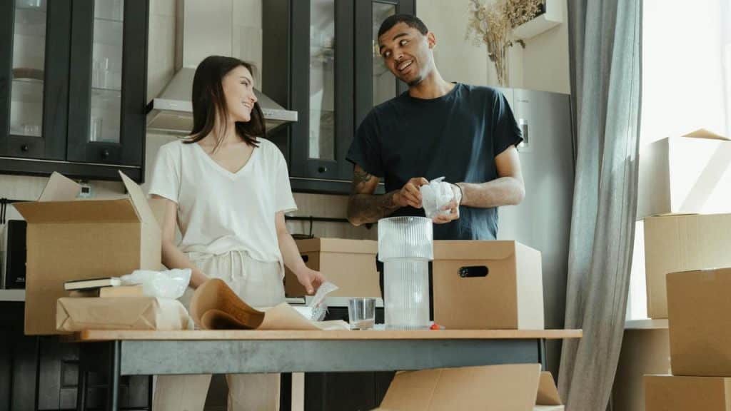 A couple unpacking boxes together in a kitchen while smiling