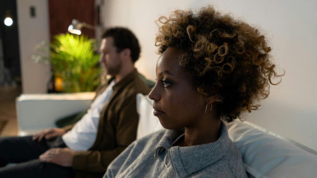 Side profile of a woman with curly hair sitting on a couch near a man.