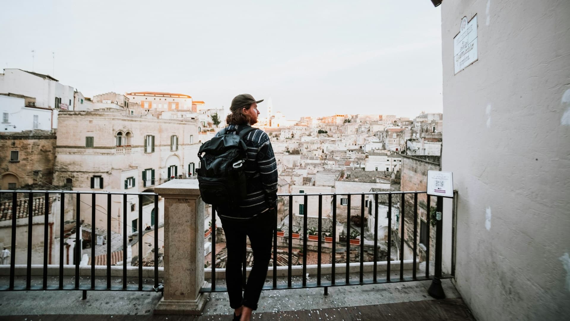 A man standing on a balcony overlooking the city.