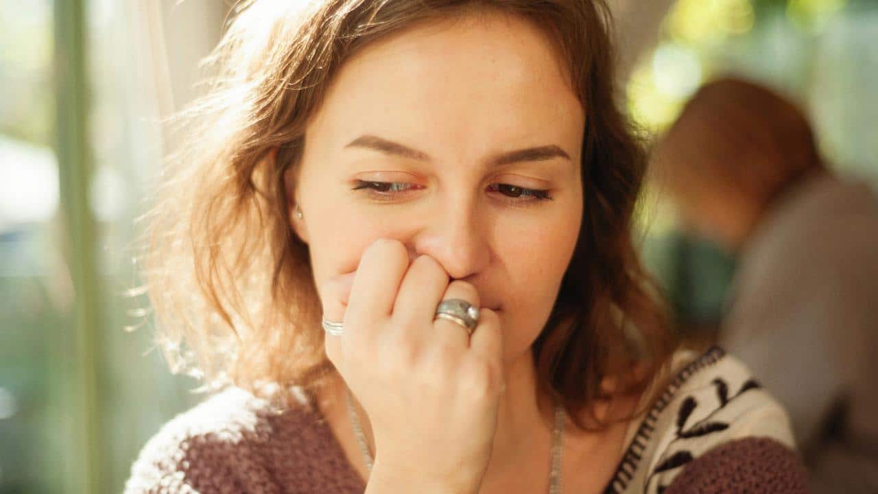 A woman resting her hand near her mouth in thought.