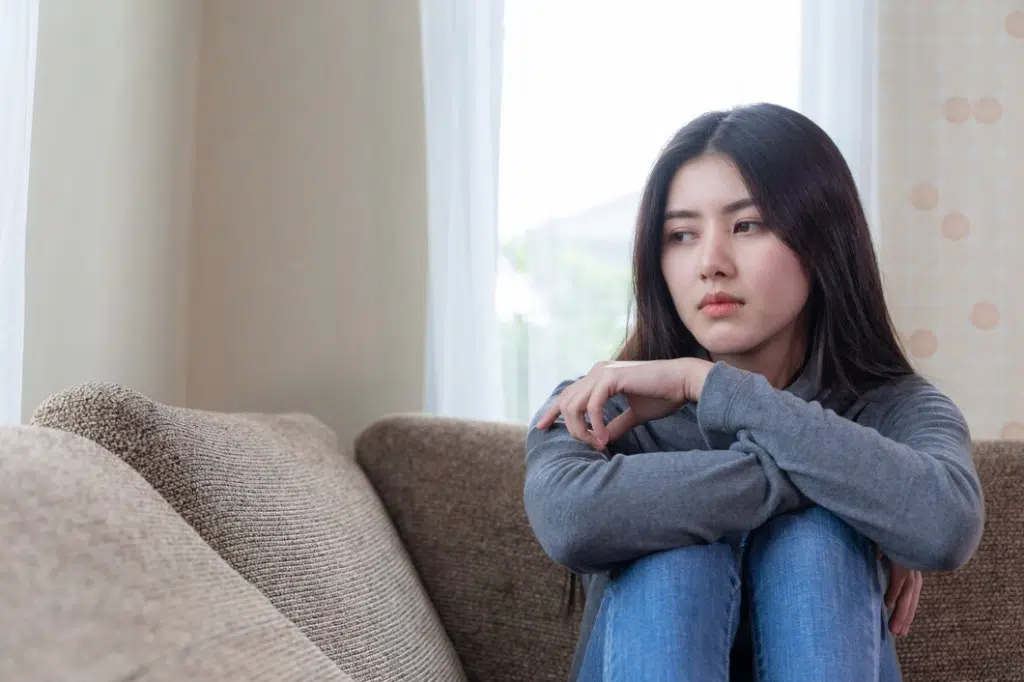Unhappy woman sitting alone on couch