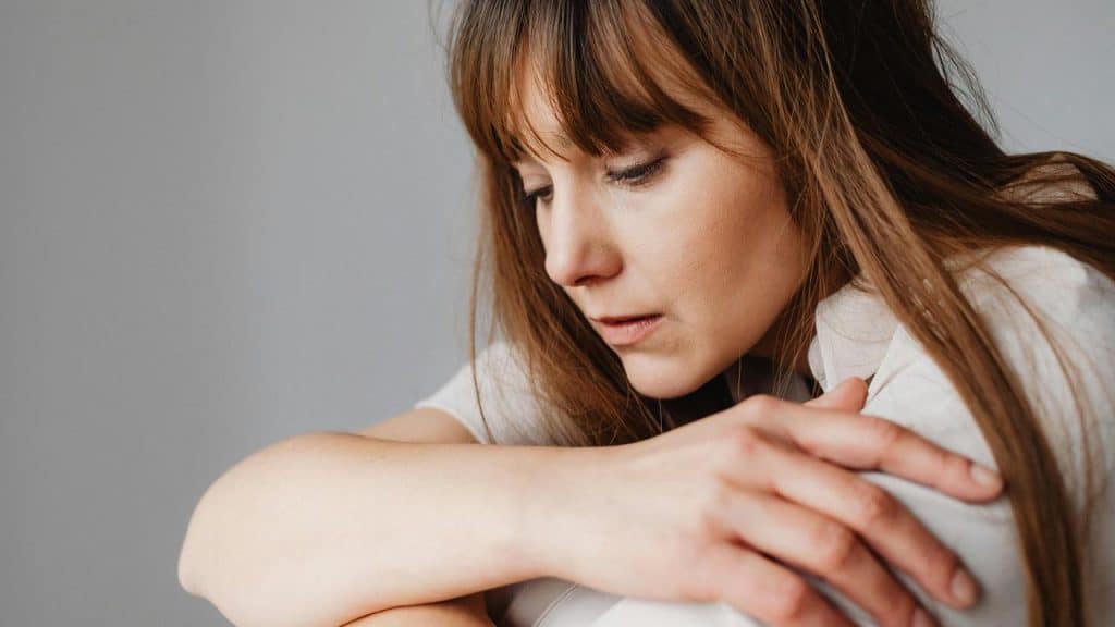 A sad woman resting her arms and looking down thoughtfully.