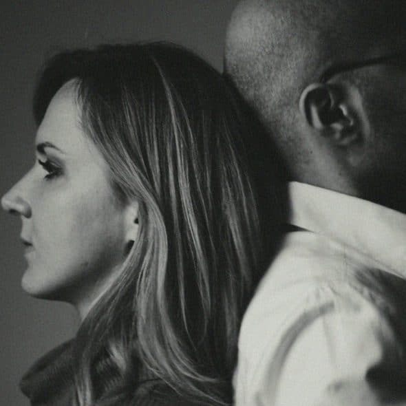 A black and white profile photo of a woman and man leaning back to back.
