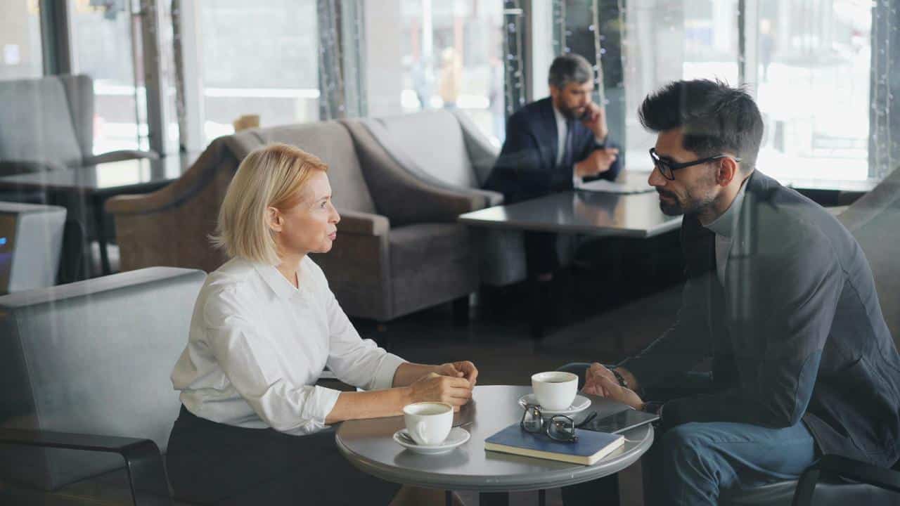 A man and a woman having a serious conversation over coffee in a modern café.