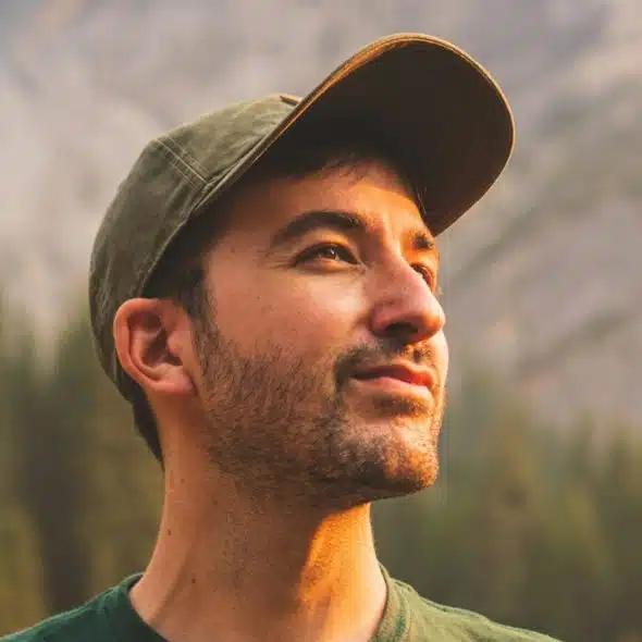 A man in a green crewneck shirt and green cap.