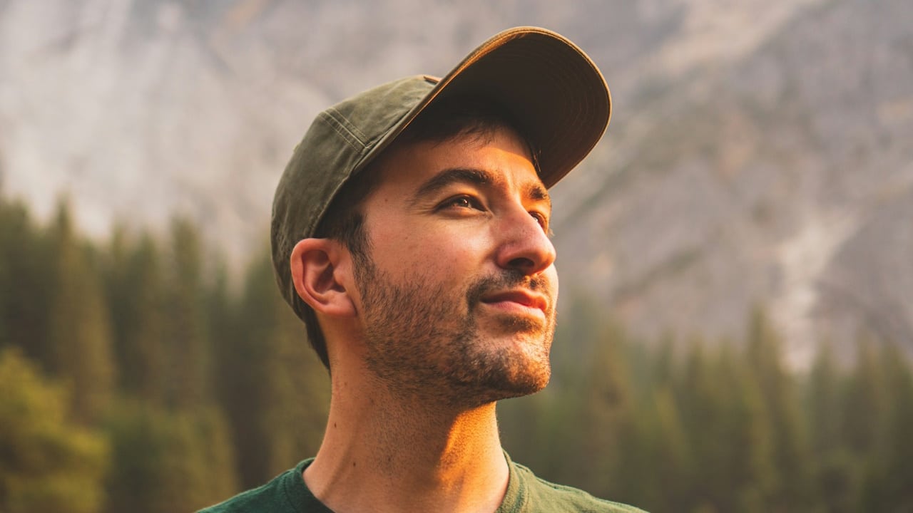 A man in a green crewneck shirt and green cap.