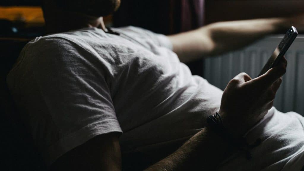 A person lying down while using a smartphone.