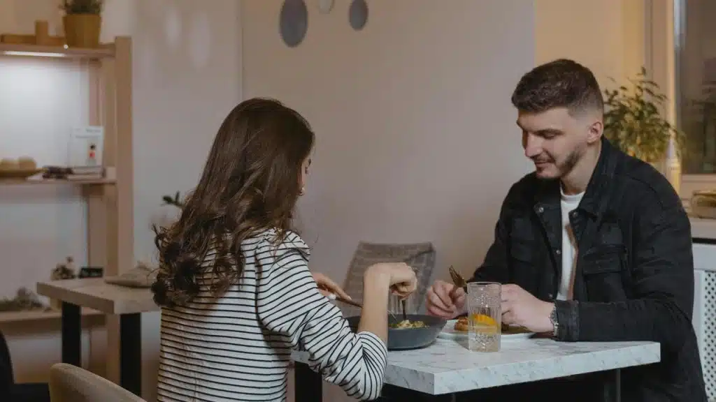 A man and woman sitting at a table eating together in a cozy restaurant.