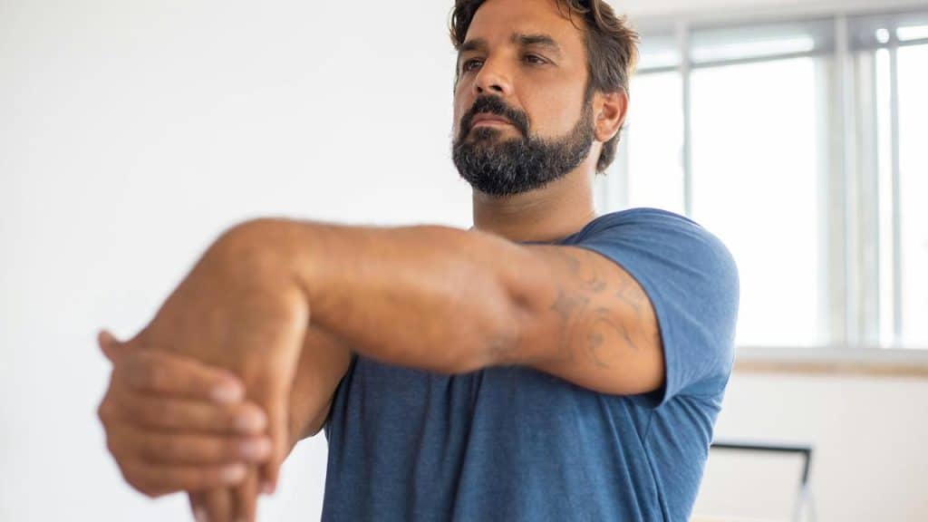 A man stretching his arm indoors.