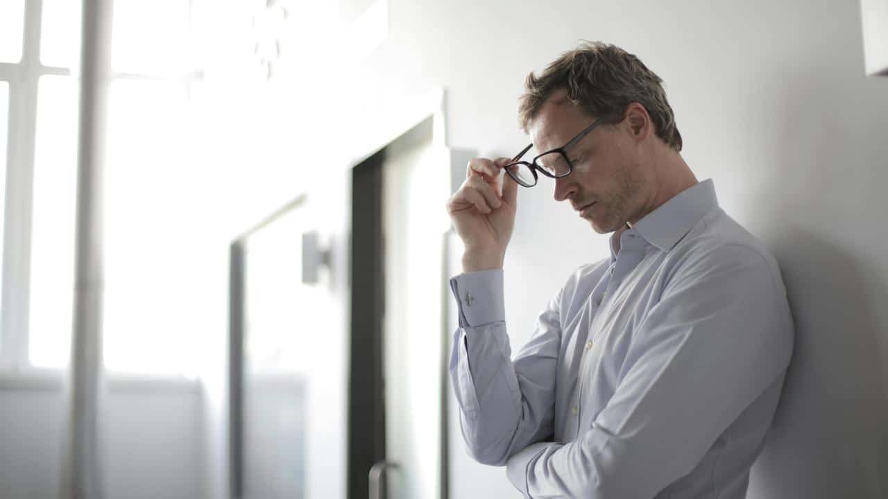 A worried man leaning against a wall