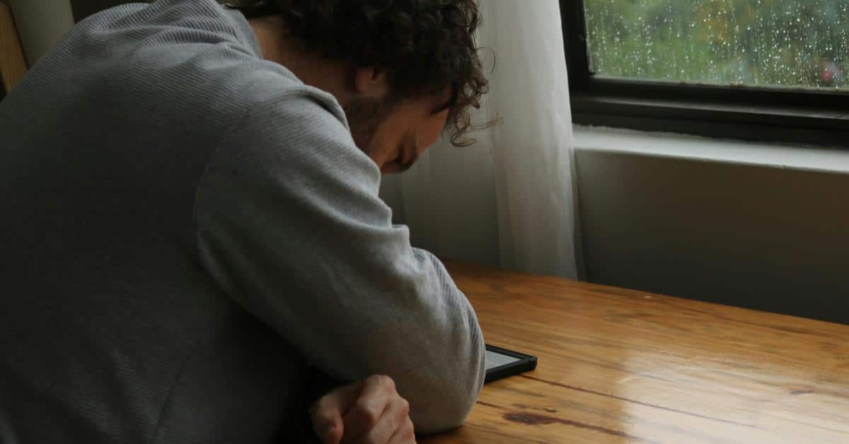 A man resting his head on his arm beside a phone