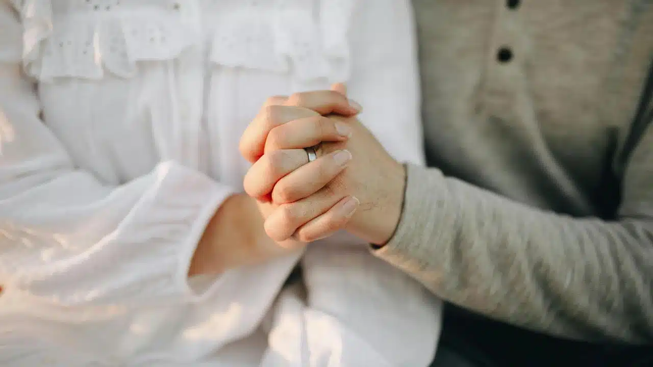 A couple holding hands closely together.