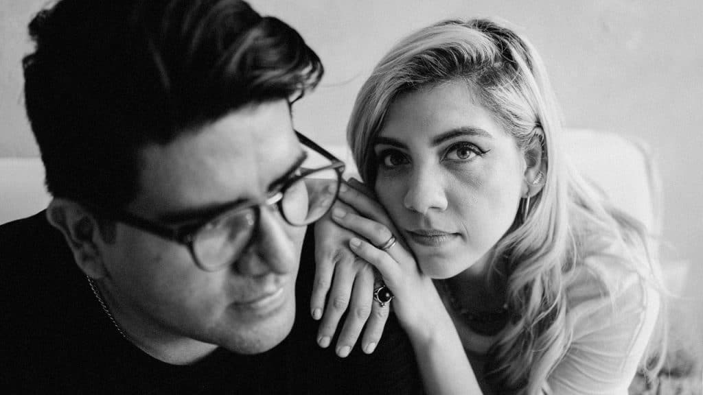 Black and white close-up of a man in glasses and a woman with light hair.