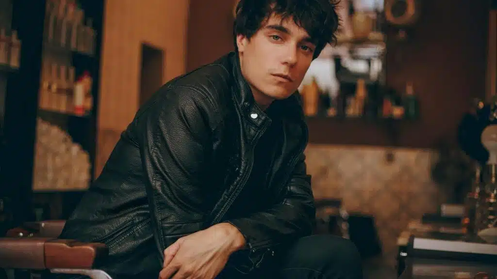 A man in a leather jacket sitting indoors.