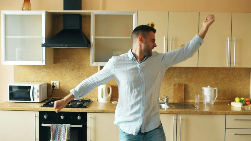 A man dancing happily in a modern kitchen.