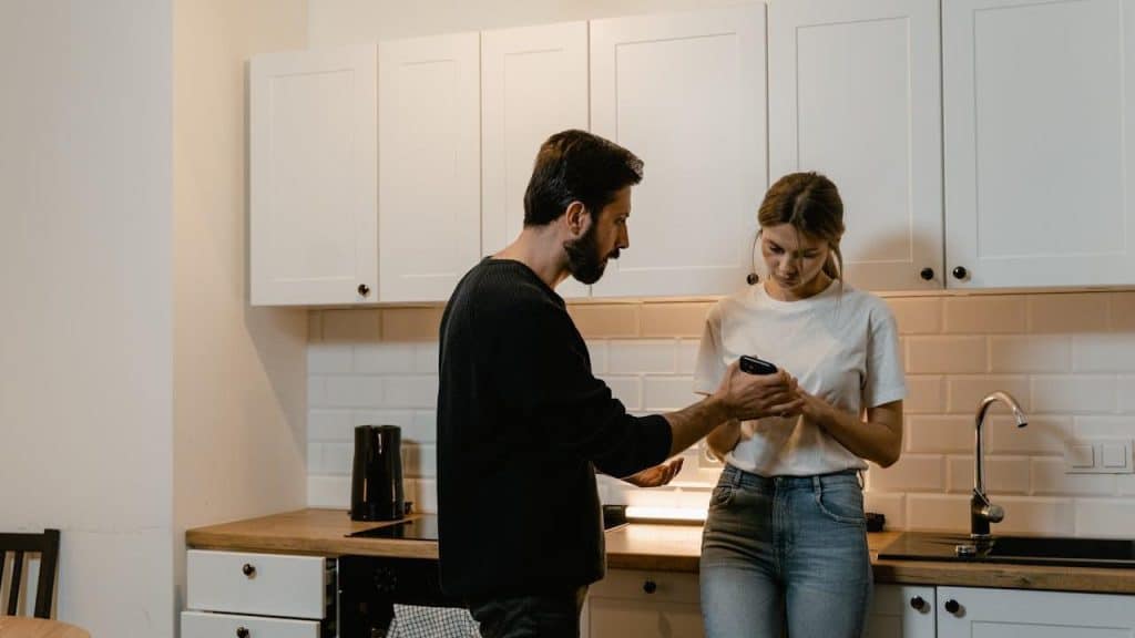 A serious man takes the phone from his wife’s hand, who is being very upset.