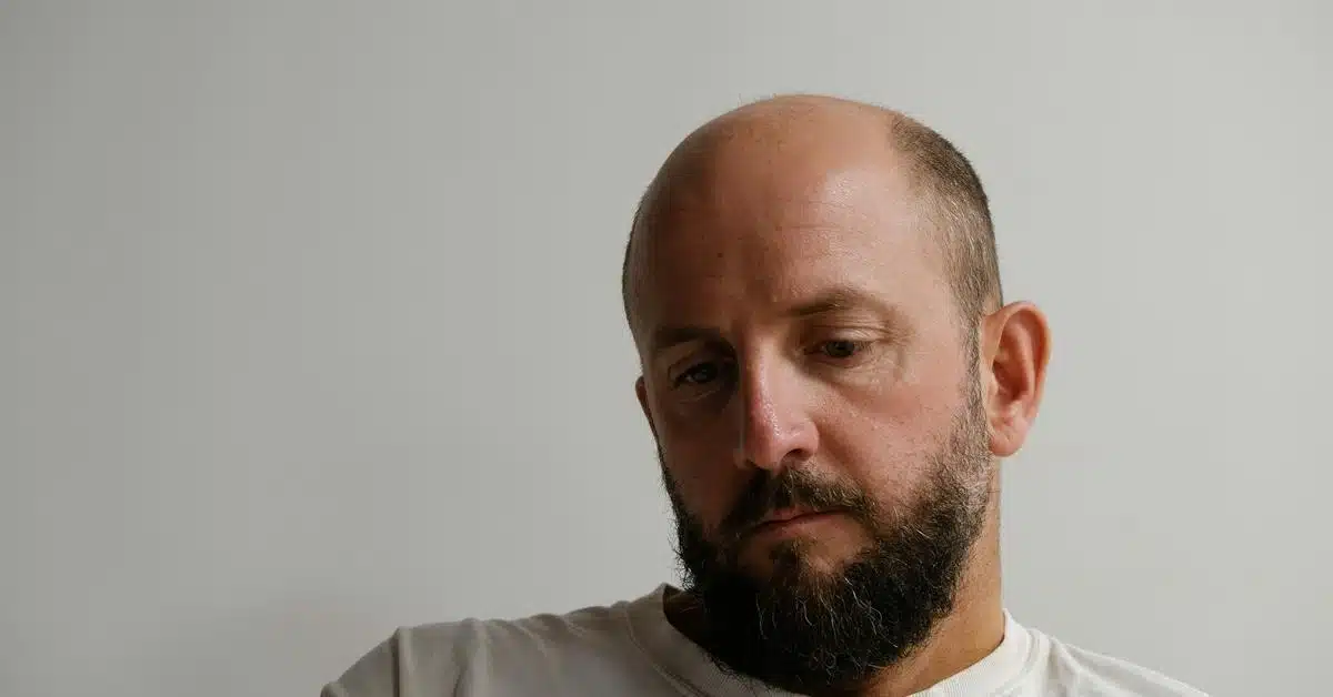 A bearded man looking down