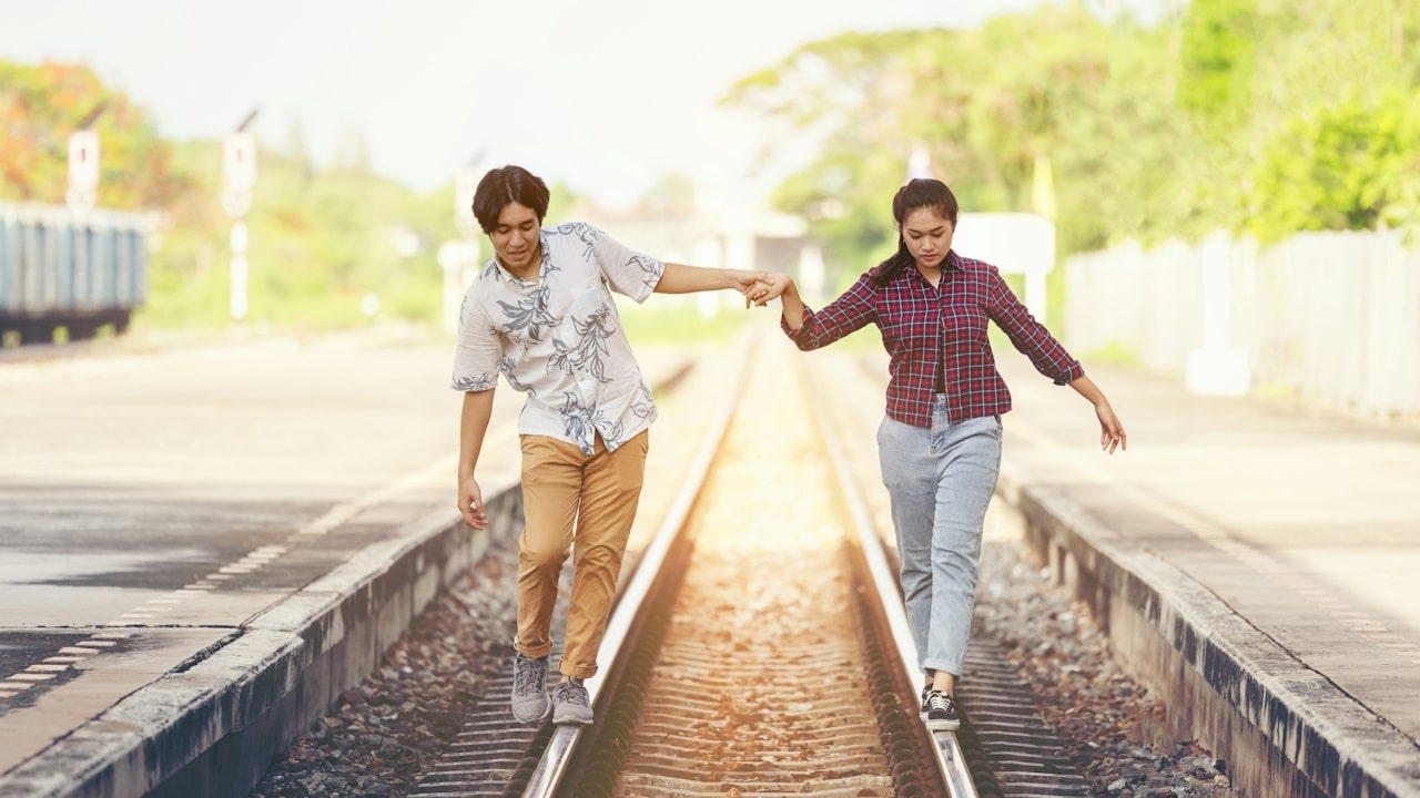 A couple walking side by side on a railway