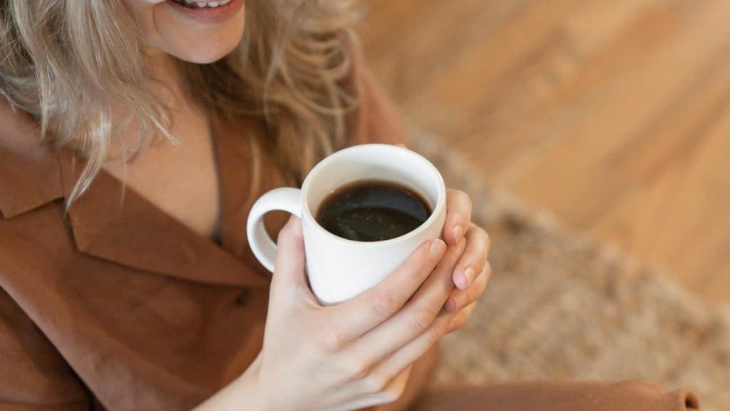 A woman holding a mug of coffee and smiling.