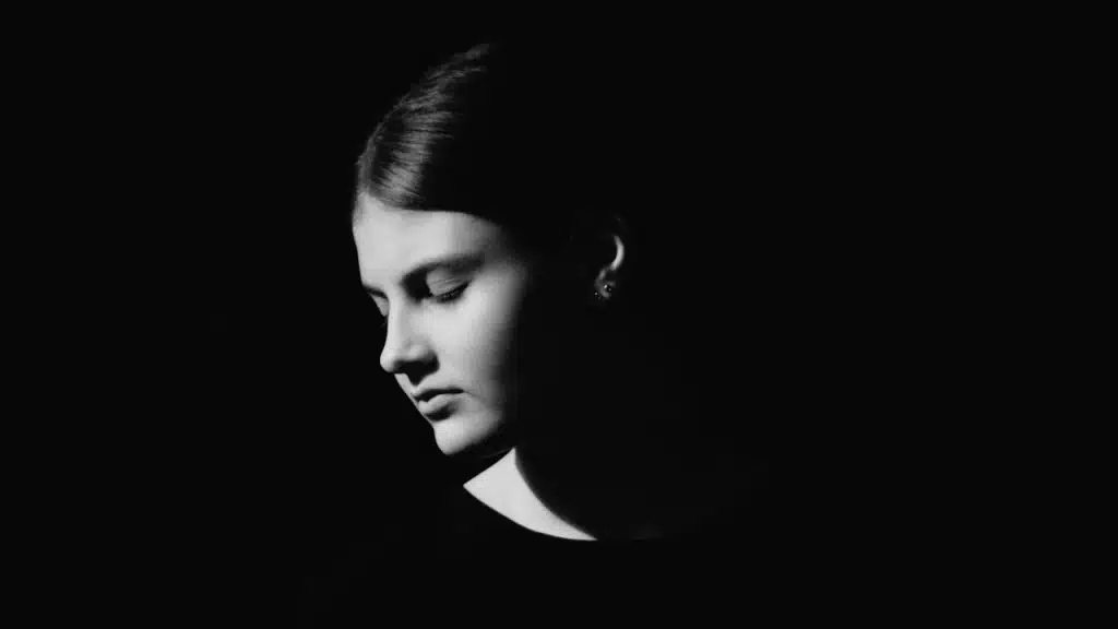 A closeup of a woman sitting in dark.
