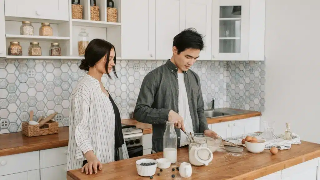 A couple preparing food together in a kitchen.
