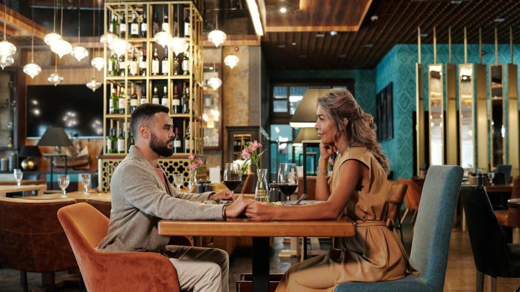 A couple holding hands across a table during a romantic restaurant dinner.
